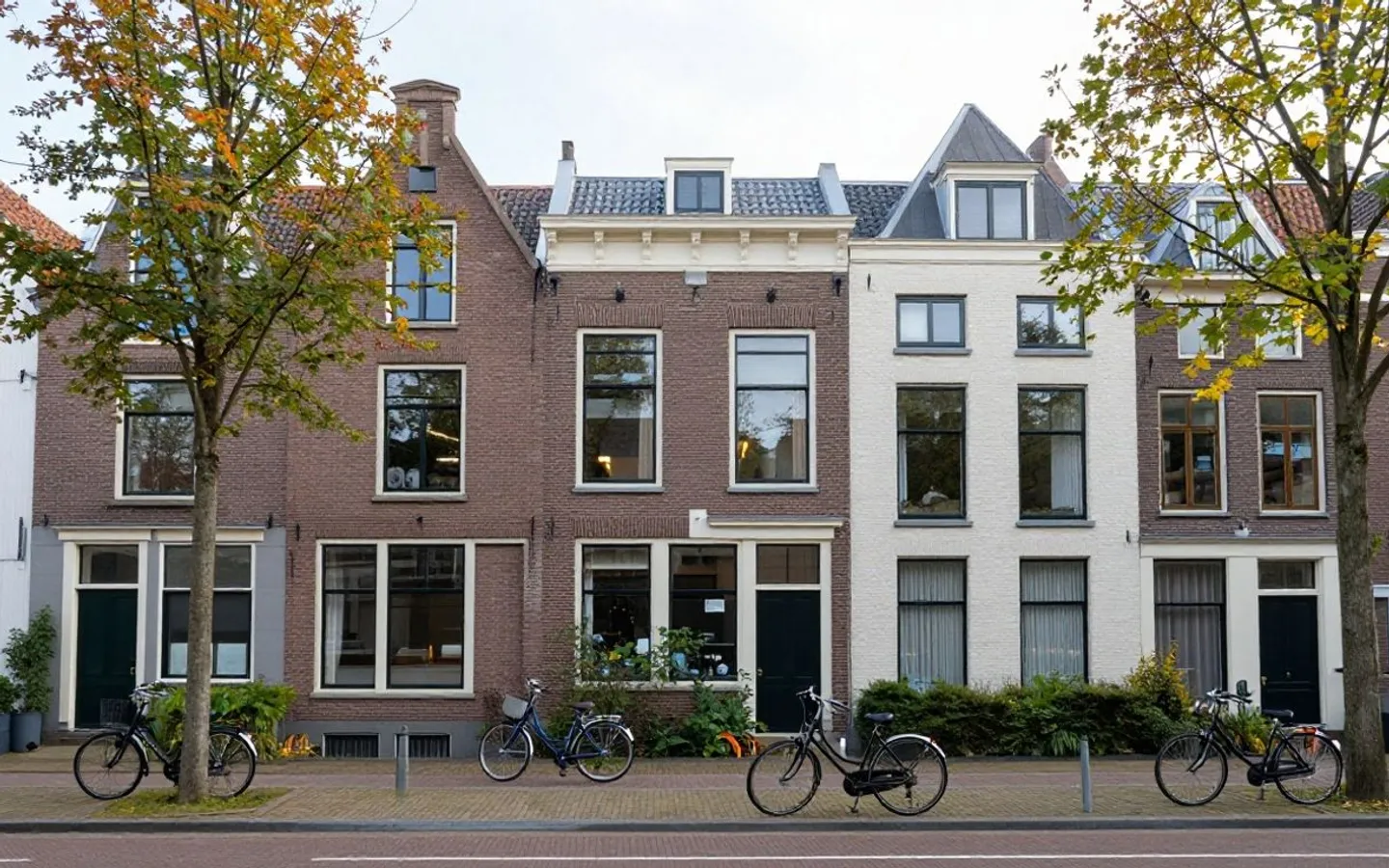 Een rij grachtenpanden met verspringende gevels, weerspiegeld in het water.